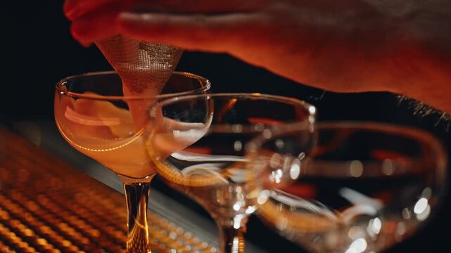 Bartender hands filtering ingredient cocktail in barware at nigthclub closeup.