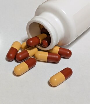 Vista de cerca de c&aacute;psulas derramadas de una botella blanca de pl&aacute;stico abierta 