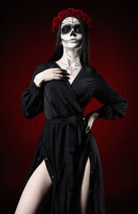Young woman with calavera (sugar skull) makeup. The witch girl with muertos (muerte) greasepaint in...