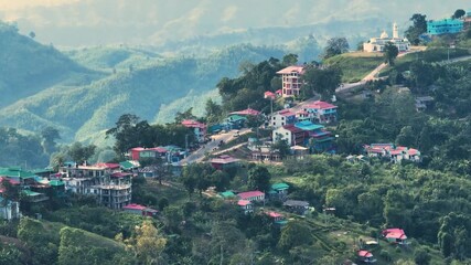 Sajek, Bangladesh - 21 August 2025: Aerial view of the village's vibrant buildings nestled within lush green hills, showcasing a blend of residential and religious structures.