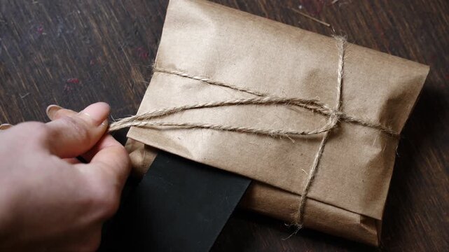 Close-Up Placing Leather Piece Under Knot on Wrapped Wallet