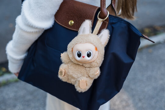 Tallinn, Estonia - Aug 26, 2025: Labubu figurine hanging on girl's bag. Blind box packaging. Excitement of surprise toy reveals. Dangerous phthalate levels.