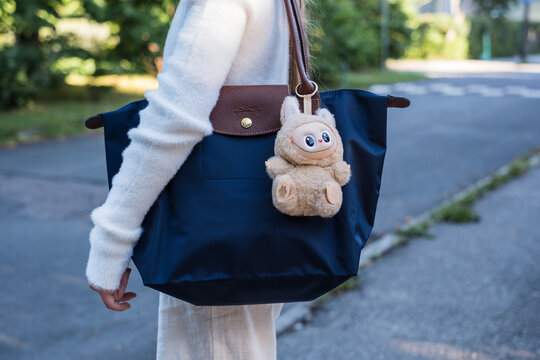 Tallinn, Estonia - Aug 26, 2025: Labubu figurine hanging on girl's bag. Blind box packaging. Labubu Toy from Pop Mart &ldquo;Have A Seat&rdquo; Series. Dangerous phthalate levels.