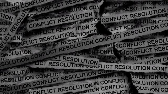 Strips of newspaper with the words Conflict Resolution typed on them. Black and white. Close up.