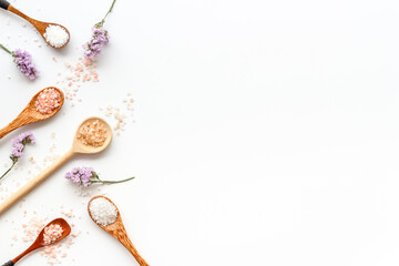 Obraz na płótnie Canvas Beauty spa therapy cosmetics and wellness flat lay - sea salt in many spoons with flowers, top view