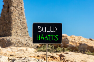 Build habits symbol. Concept word Build habits on beautiful black blackboard. Beautiful stone and blue sky background. Black blackboard. Business build habits concept. Copy space.