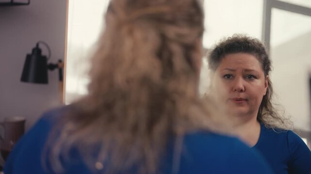 Overweight woman unhappy with reflection in mirror, self-doubt and insecurities