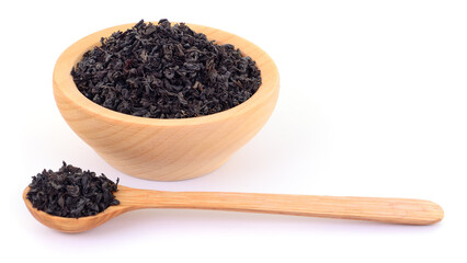 Black tea leaves in wooden bowl and spoon isolated on white background