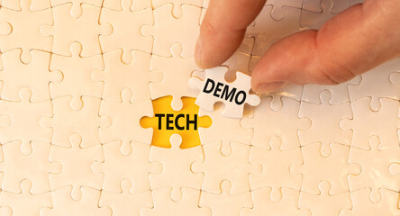 Tech demo symbol. Concept word Tech demo on beautiful white puzzles. Businessman's hand. Beautiful yellow paper background. Business tech demo concept. Copy space.