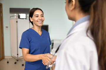 Obraz premium Happy Middle Eastern doctor woman shaking hands with female colleague