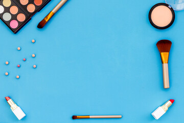 Flatlay of makeup cosmetics on blue background. Blusher, mascara and lipstick, top view