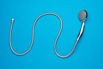 Modern Silver Shower Head with Flexible Hose on Vibrant Blue Background