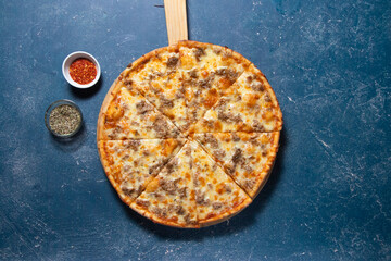 Classic Tonno e Cipolla Pizza with Tuna and Onion isolated on wooden cutting board on a Dark Blue Background top view of fast food