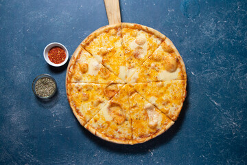 Four Cheese Pizza with Melted Mozzarella and Herbs isolated on wooden cutting board on a Dark Blue Background top view of fast food