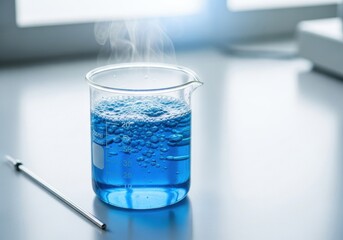 Blue liquid with bubbles and steam in a beaker on a light gray table. Laboratory experiment and scientific research concept.