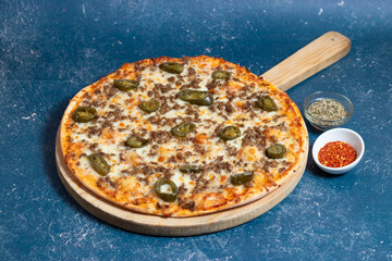 Spicy La Mexicana Pizza with Savory Ground Beef and Jalapeno Peppers isolated on wooden cutting board side view of fast food