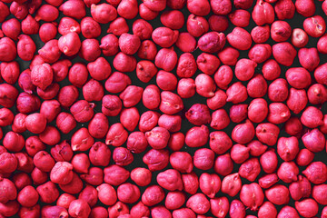 Texture of dyed chickpeas in bright red color. Decorative background of legumes. Healthy vegetarian food grains. Abstract closeup pattern with colorful seeds. Natural organic texture for culinary.