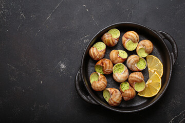Bourgogne snails baked with garlic and parsley butter, served in a cast iron pan with lemon slices,...