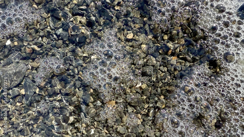 Poster shimmering river pebbles under clear water with natural bubble clusters creating abstract stone surf