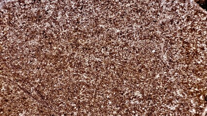 closeup of rough brown granite surface with sparkling mineral reflections ideal for natural stone background or texture design