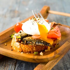 Poached egg on toast with anchovies and tomatoes