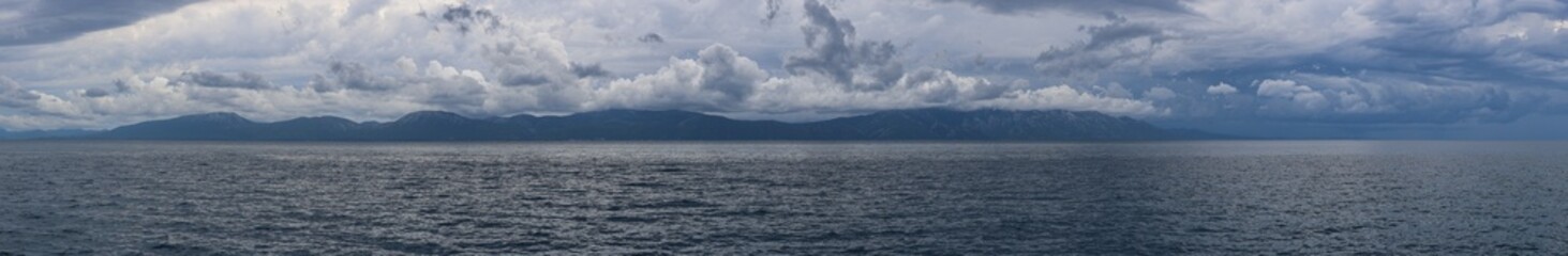Stormy sky over mountains and sea. Dark dramatic clouds hang over the water surface, creating an atmosphere of tension and grandeur of nature. Podaca village, Makarska Riviera, South Dalmatia, Croatia