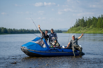 Three happy fishermen in a boat with spinning rods on a river