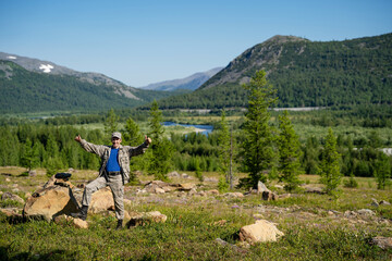 Hunter stands and shows thumbs up against the backdrop of a panorama of moun