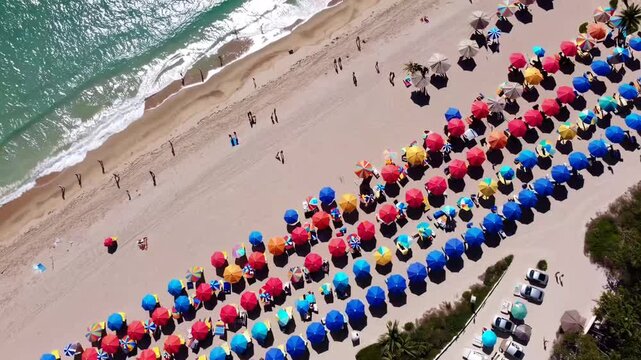 direct aerial overview of vibrant teal ocean seashore and colorful beach umbrellas on Florida beach
