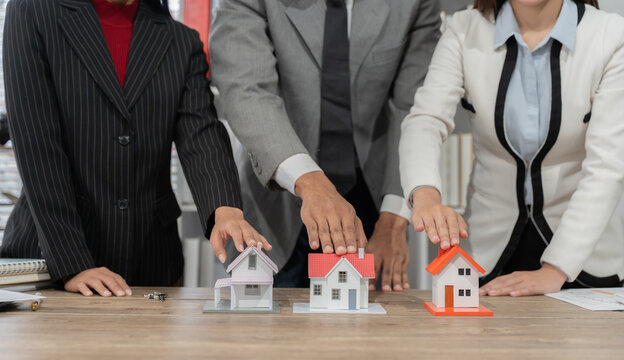 Real Estate Showcase: A diverse team of professionals gathers around miniature house models, symbolizing investment opportunities and the promise of a new home.