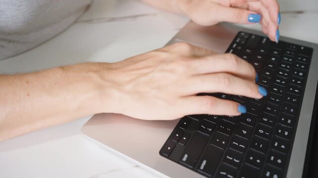 Close Up of Right Hand with Veins Visible Typing on Black Keyboard with Blue Nails
