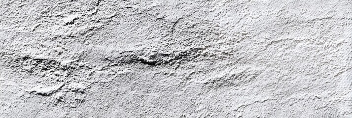 Textured grayscale image showing a rough, uneven surface with subtle variations in shade, resembling a weathered stone or plaster wall with faint, dark linear cracks