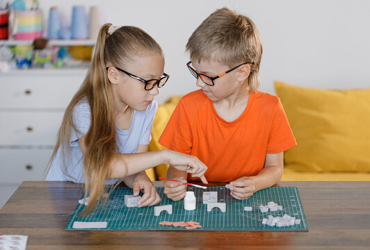 Boy and girl in glasses assembling constructor at school desk. Educational STEM activity for children developing creativity, teamwork, and problem-solving skills.