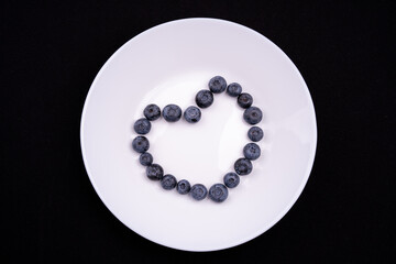 Blueberries on a white plate with isolated black background