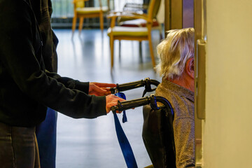 elderly person in wheelchair entering elevator, assisted by caregiver. daily life, dependence and...