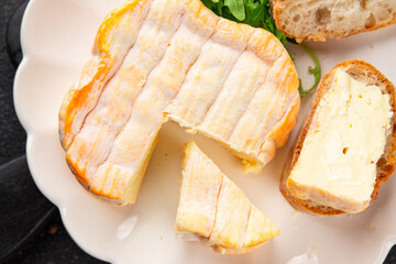 Washed rind cheese soft cheese with orange rind munster french cheese tasty snack fresh delicious gourmet food background on the table rustic top view copy space