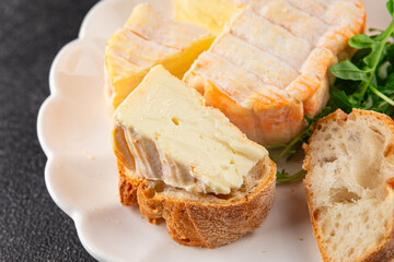 Washed rind cheese soft cheese with orange rind munster french cheese tasty snack fresh delicious gourmet food background on the table rustic top view copy space