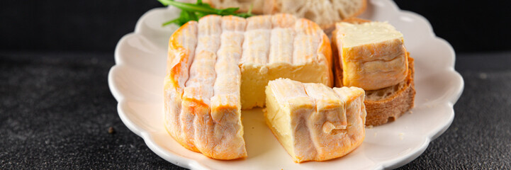 Washed rind cheese soft cheese with orange rind munster french cheese tasty snack fresh delicious gourmet food background on the table rustic top view copy space