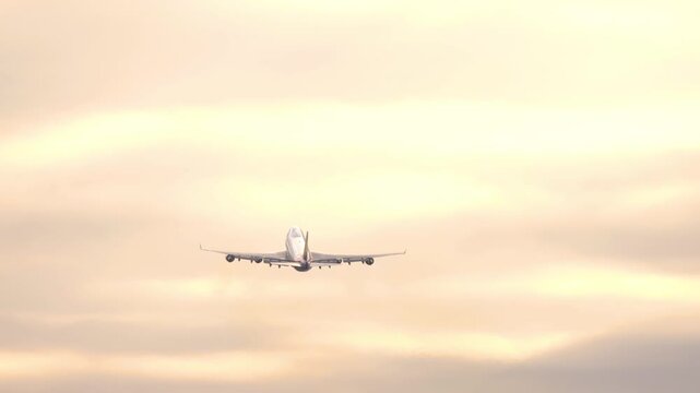 Widebody four-engine jet climbing into the sky at sunrise or sunset. Travel and long-haul aviation concept.