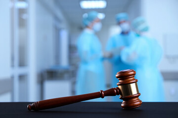 Gavel on a table in front of blurred medical professionals