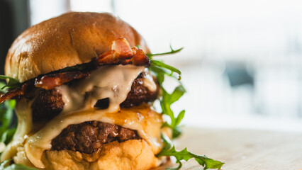 A towering double-deck bacon cheeseburger with juicy, rare beef patties, melted cheese, and crispy...