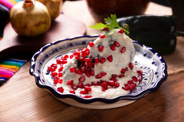 Chiles en Nogada, a typical Mexican dish. Poblano chile stuffed with meat and fruit, topped with a...