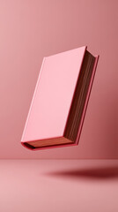 A pink book appears to levitate against a solid pink background, showcasing a minimalist and modern aesthetic.