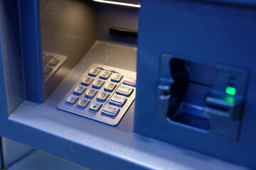 ATM card slot close view with green light and numeric keypad