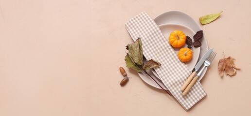 Beautiful table setting with fresh pumpkins, acorns and autumn leaves on beige background with...