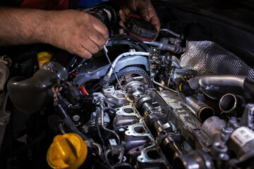 Mechanic Working on Disassembled Car Engine with Flashlight and Screwdriver