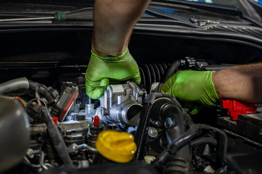 Mechanic Working on Car Carburetor Under Hood