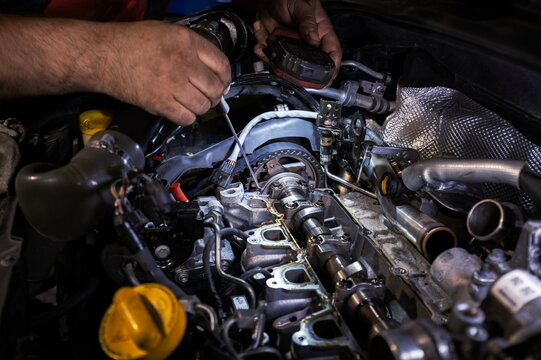 Mechanic Working on Disassembled Car Engine with Flashlight and Screwdriver