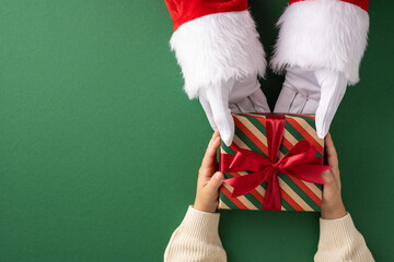 Santa Claus hands presenting a wrapped Christmas gift with red ribbon to a child's hands