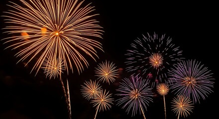 Fototapeta premium Bright orange and purple fireworks exploding in a dark night sky celebration explosion